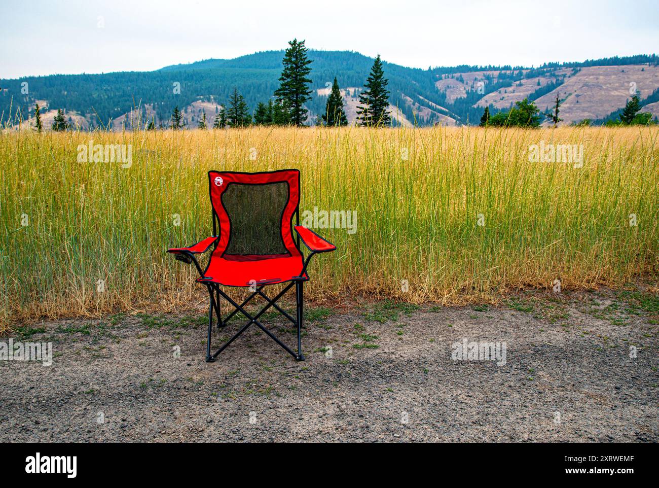 Ein leerer roter Stuhl wartet auf einen Sitter auf einer unbefestigten Straße in den Blue Mountains, Oregon. Stockfoto