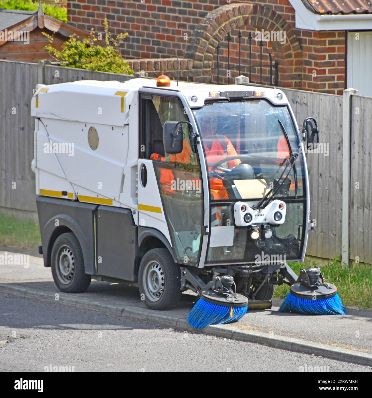 Straßenbreite Bucher mechanische Doppelbürsten-Kehrmaschine und Fahrer am Standort des Arbeitsdorfes, Fahrt entlang des Weges für Brentwood Council Essex England UK Stockfoto