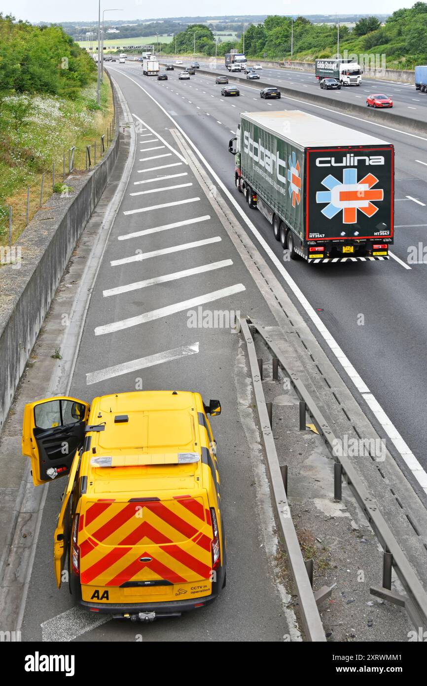 AA Pannenwagen parkt auf der Autobahn M25 hart Schulter ein Mechaniker, der an einem Pannenfahrzeug arbeitet, das unter der Straßenbrücke Essex England UK nicht zu sehen ist Stockfoto