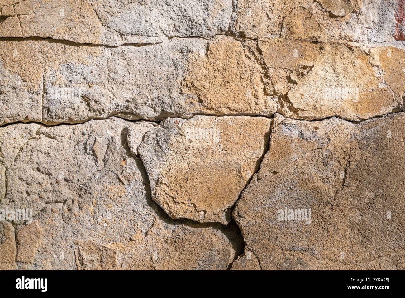 Ein Riss an der Steinmauer eines Gebäudes. Hintergründe und Texturen. Stockfoto