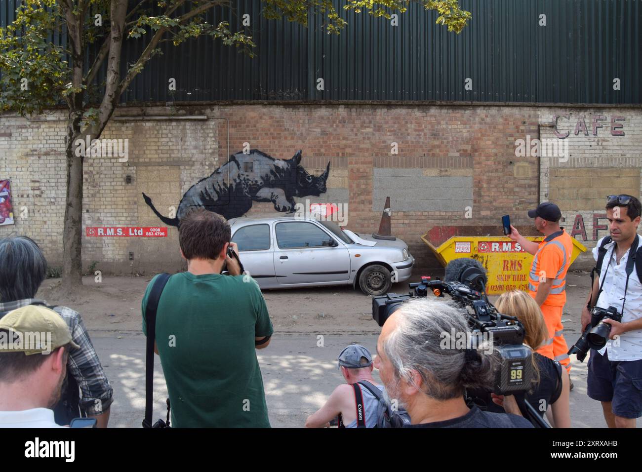 London, Großbritannien. August 2024. Fotografen und Fans treffen sich bei einem neuen Kunstwerk von Banksy an einer Wand in Charlton, das ein Nashorn zeigt, das sich mit einem Auto mit einem Verkehrskegel auf der Motorhaube intim fühlt. Dies ist das 8. Neue Tierwerk in acht Tagen in der Hauptstadt von dem schwer fassbaren Straßenkünstler. (Foto: Vuk Valcic/SOPA Images/SIPA USA) Credit: SIPA USA/Alamy Live News Stockfoto