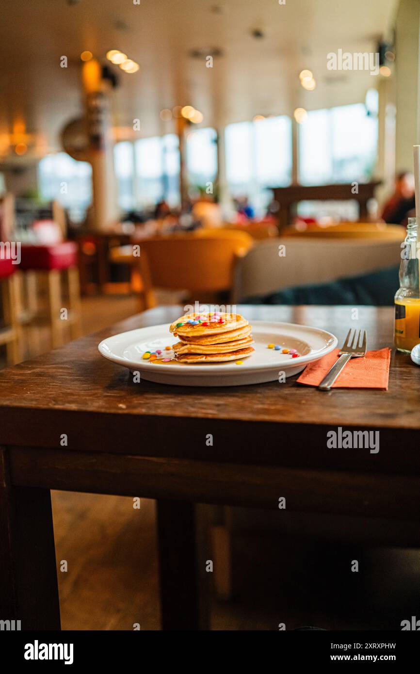 Köstlicher Stapel Pfannkuchen mit bunten Schokoladenlinsen und süßem Honig Stockfoto