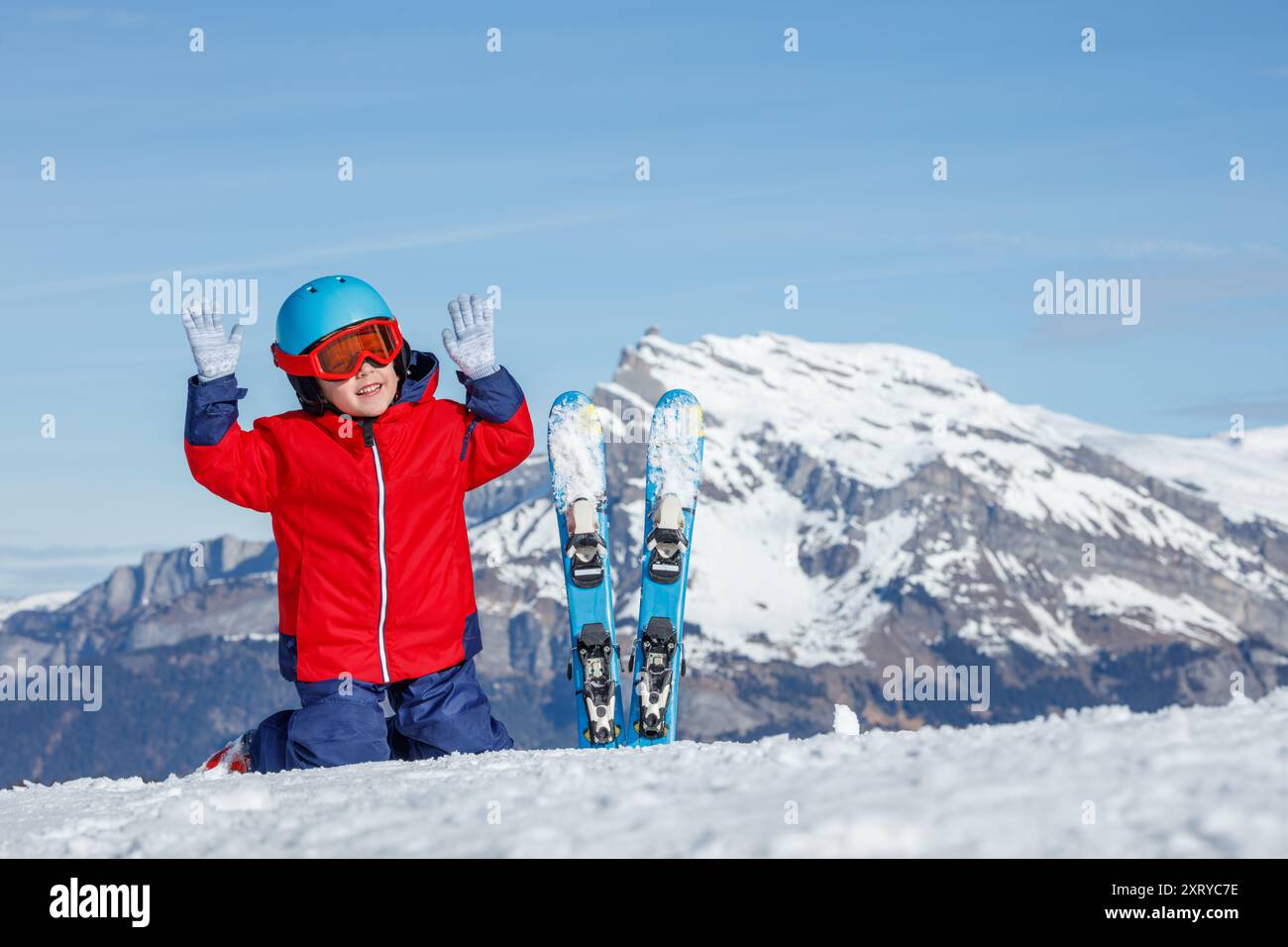 Kniend im Schnee, ein glücklicher Skifahrer im leuchtenden roten Fell Stockfoto