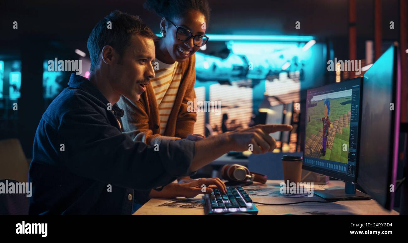 Porträt des jungen Creative Director und weiblichen Designers, der über die Arbeit spricht und Änderungen am Projekt vornimmt. Zwei stilvolle, vielfältige Mitarbeiter diskutieren in Game Development Company über Level Landscape on Computer Stockfoto