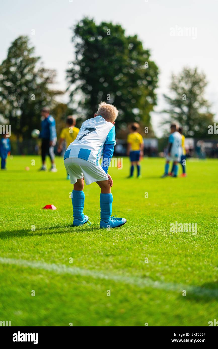 Junger Fußballspieler in weißem und blauem Trikot, der am Rande steht und darauf wartet, aktiviert zu werden Stockfoto