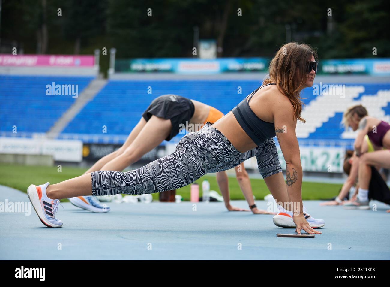 Athletische ukrainische Frau, die im Sommer während des Gruppenfunktionstrainings im Freien dehnt. Kiew - 10. August 2024 Stockfoto