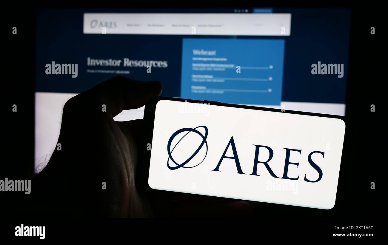 Person, die ein Mobiltelefon mit dem Logo der amerikanischen Investmentgesellschaft Ares Management Corporation vor der Webseite hält. Schwerpunkt auf dem Display des Telefons. Stockfoto