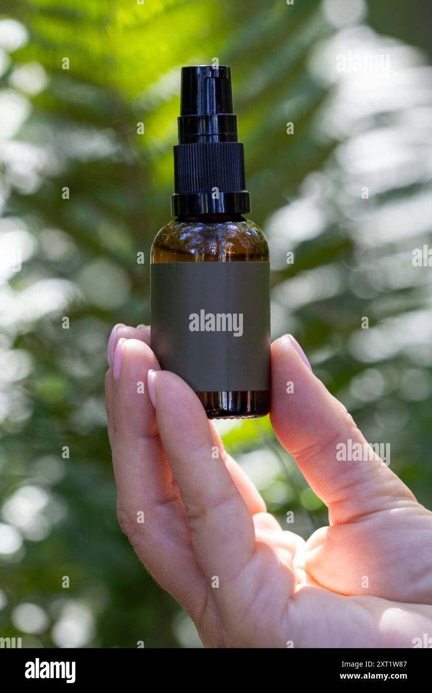 Sprühflasche in der Hand inmitten von üppigem Grün Stockfoto