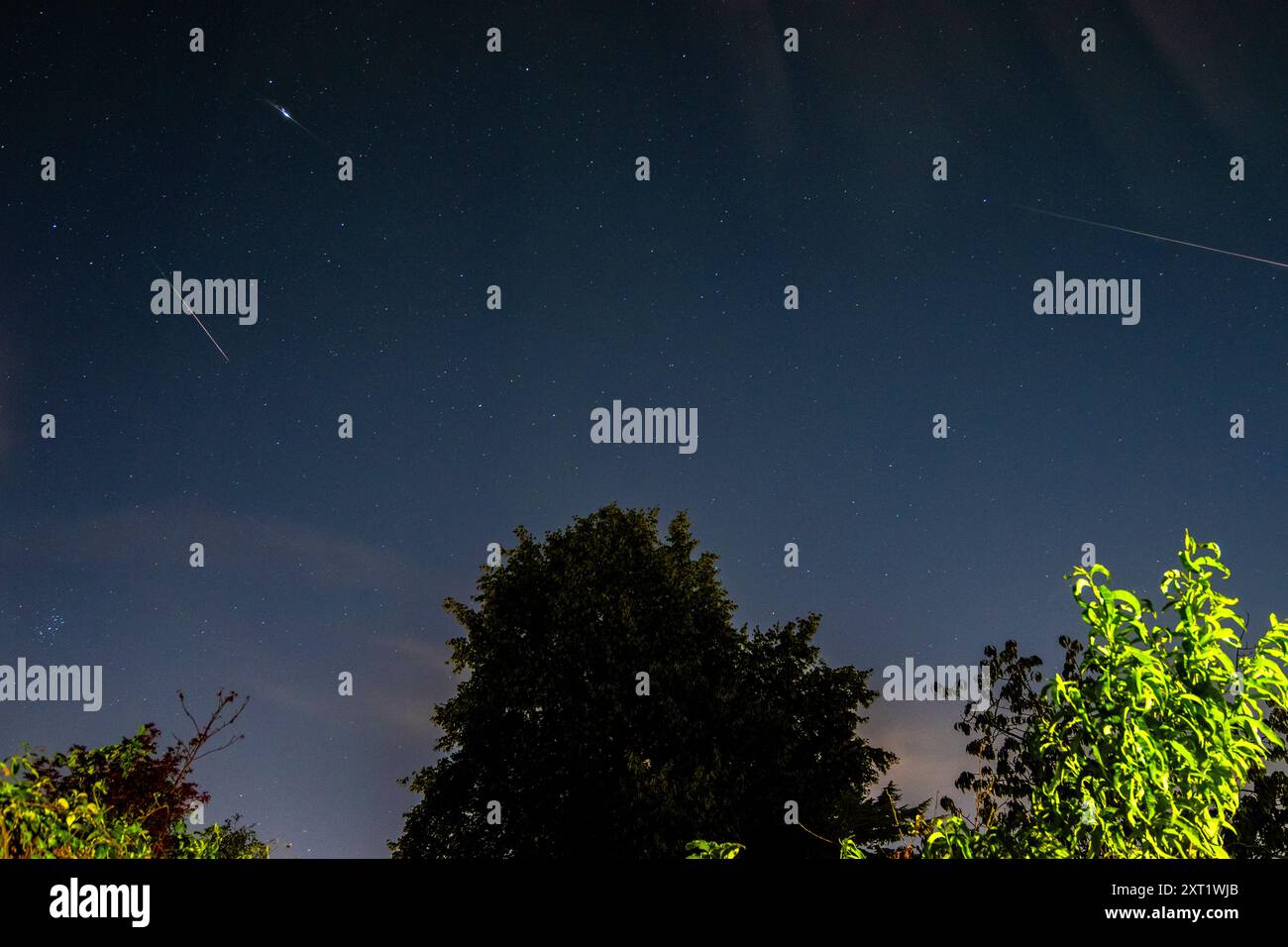 London, Großbritannien. August 2024. UK Weather – Ein zusammengesetztes Bild, das drei Meteoriten des Perseidenschauer in den frühen Morgenstunden in der Nähe von Watford im Nordwesten Londons zeigt. Der Perseiden-Meteoritenschauer ist das Ergebnis einer Staubwolke, die hinter dem Kometen Swift-Tuttle zurückgelassen wurde. Oben rechts ist die schwache Aurora Borealis (Polarlichter) zu sehen, die durch energiereiche Partikel der Sonne verursacht wird, die mit Geschwindigkeiten von bis zu 45 Millionen mph auf die obere Erdatmosphäre treffen. Quelle: Stephen Chung / Alamy Live News Stockfoto