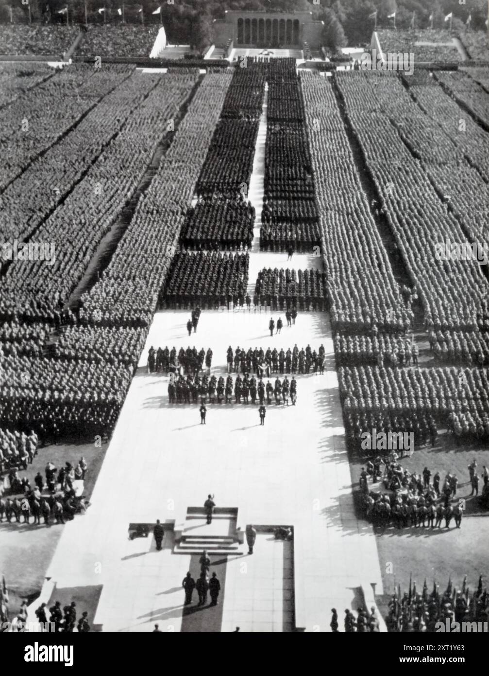 Dieses Foto zeigt Adolf Hitler, der Mitglieder der SA (Sturmabteilung), auch bekannt als Brownshirts, und des NSKK (nationalsozialistisches Motorkorps) spricht. Die SA spielte durch Einschüchterung und Gewalt eine Schlüsselrolle beim Aufstieg Hitlers an die Macht, während sich die NSKK auf motorisiertes Training und Fahrzeugwartung konzentrierte, die für die militärischen Bemühungen der Nazis von entscheidender Bedeutung waren. Beide Gruppen waren entscheidend für die Durchsetzung der NS-Ideologie und die Aufrechterhaltung der Kontrolle während des Dritten Reiches. Stockfoto