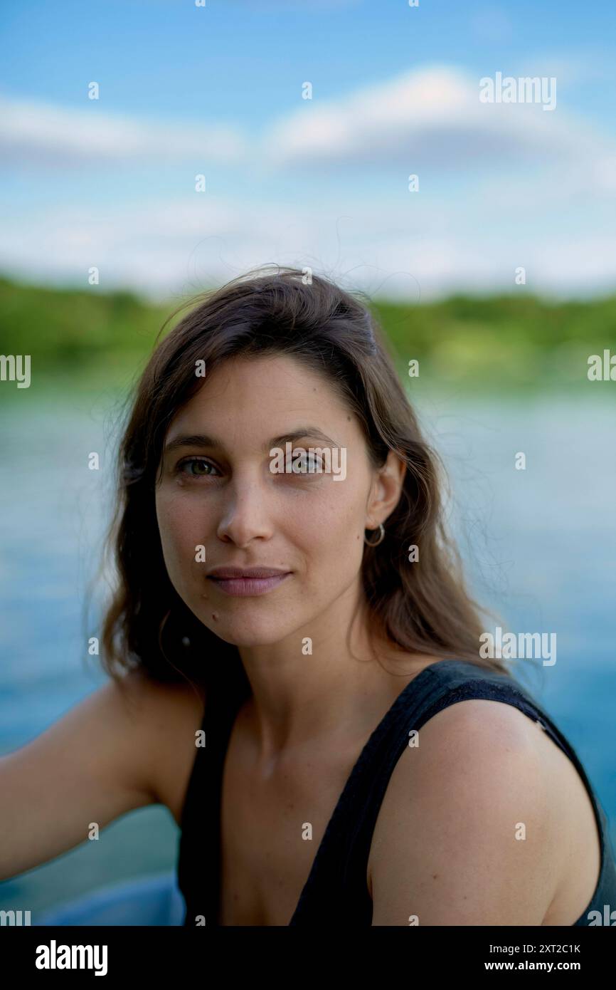 Porträt einer Frau mit braunem Haar am Wasser, die mit einem weichen Ausdruck direkt in die Kamera blickt. Bola02977 Copyright: XConnectxImagesx Stockfoto