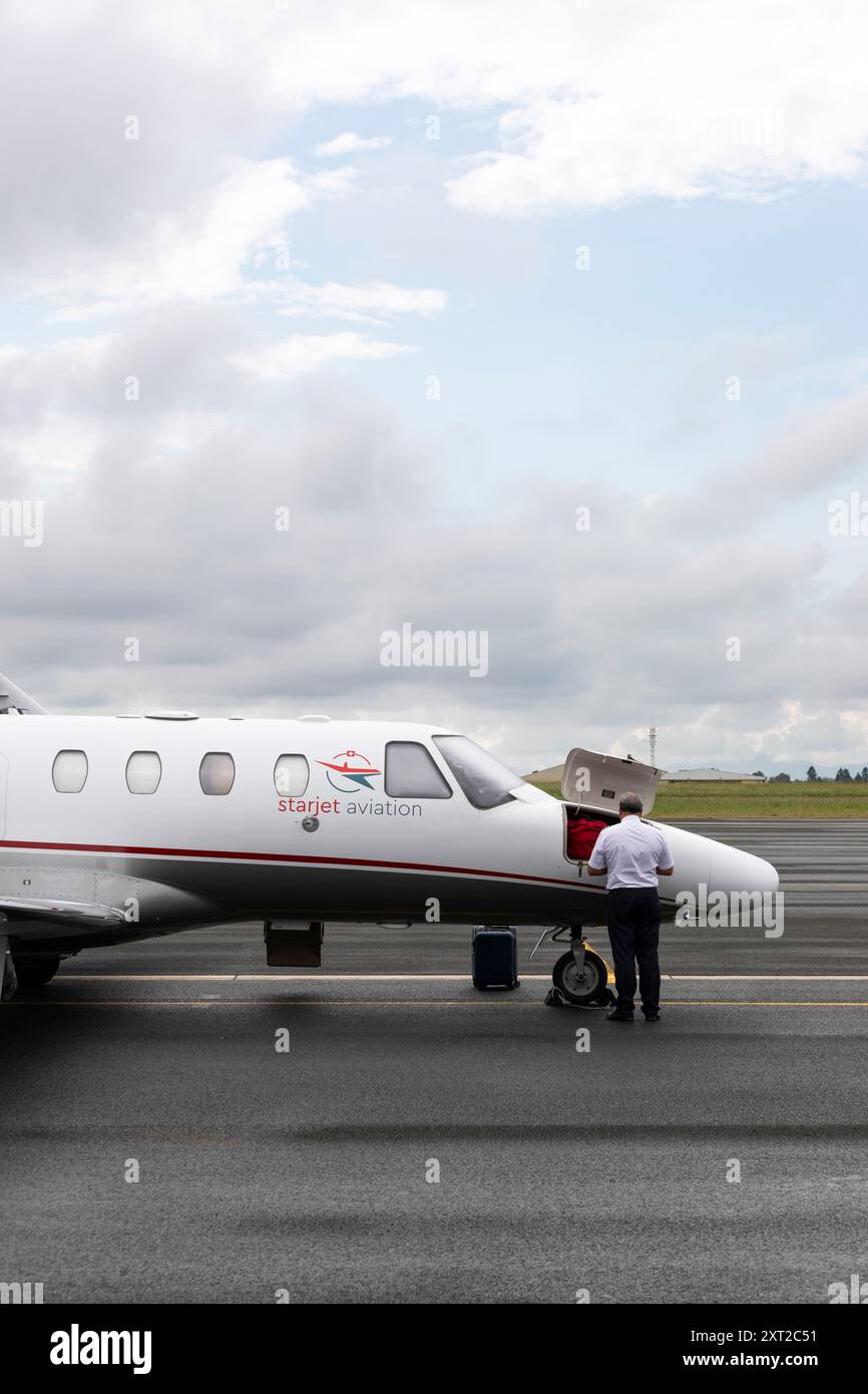 Starjet Aviation Pilot an der Vorderseite seines Flugzeugs mit geöffneter Ablageklappe an der vorderen Nase. Stockfoto