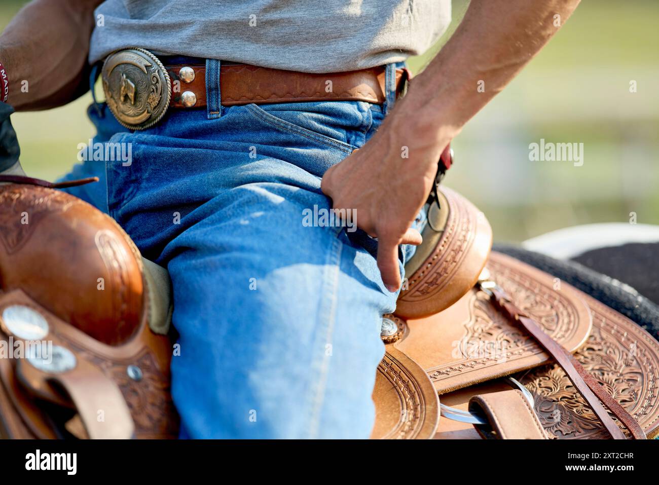 Nahaufnahme eines Cowboy-Mittelteils mit silberner Gürtelschnalle, blauer Jeans und einem detailreichen Ledersattel. Bola03068 Copyright: XConnectxImagesx RECO Stockfoto