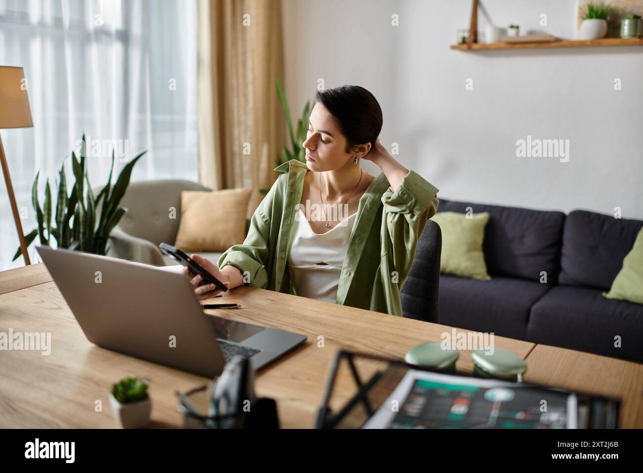 Eine Frau, die von zu Hause aus arbeitet und eine Pause einlegt, um ihr Handy zu überprüfen. Stockfoto