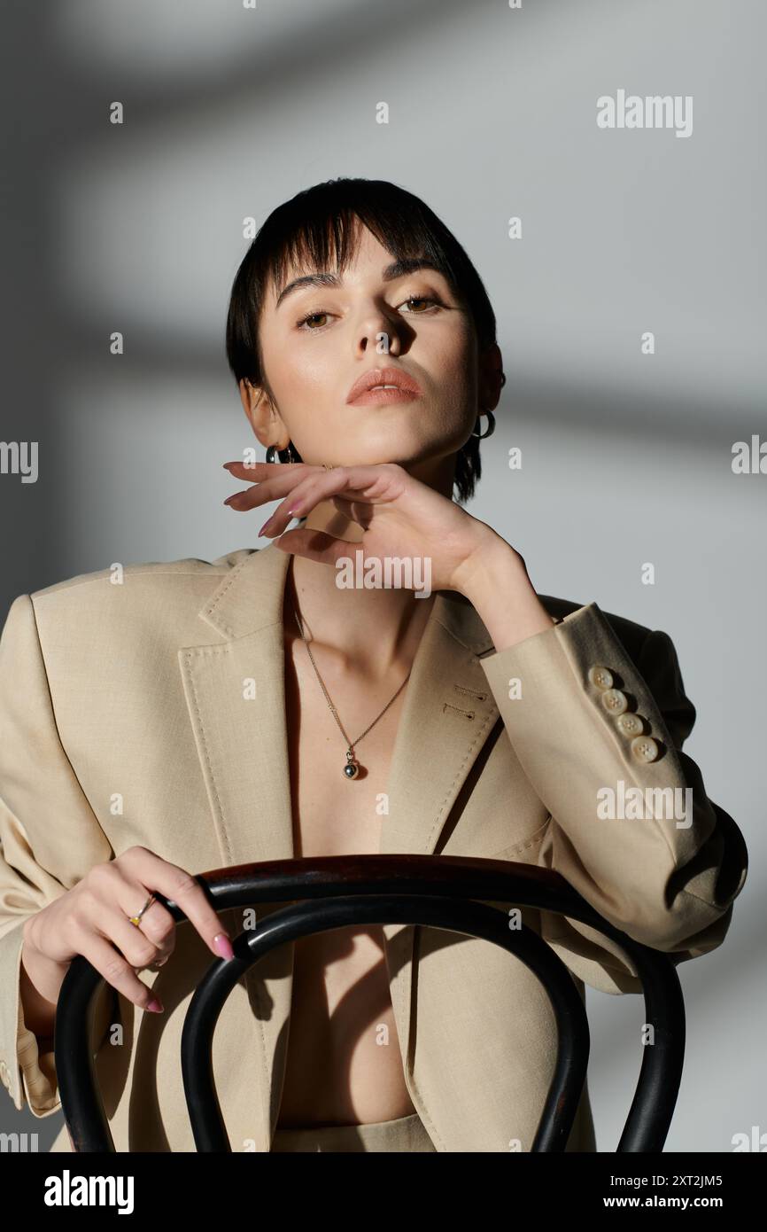 Eine Frau in einem beigefarbenen Blazer posiert mit kontemplativem Ausdruck. Stockfoto