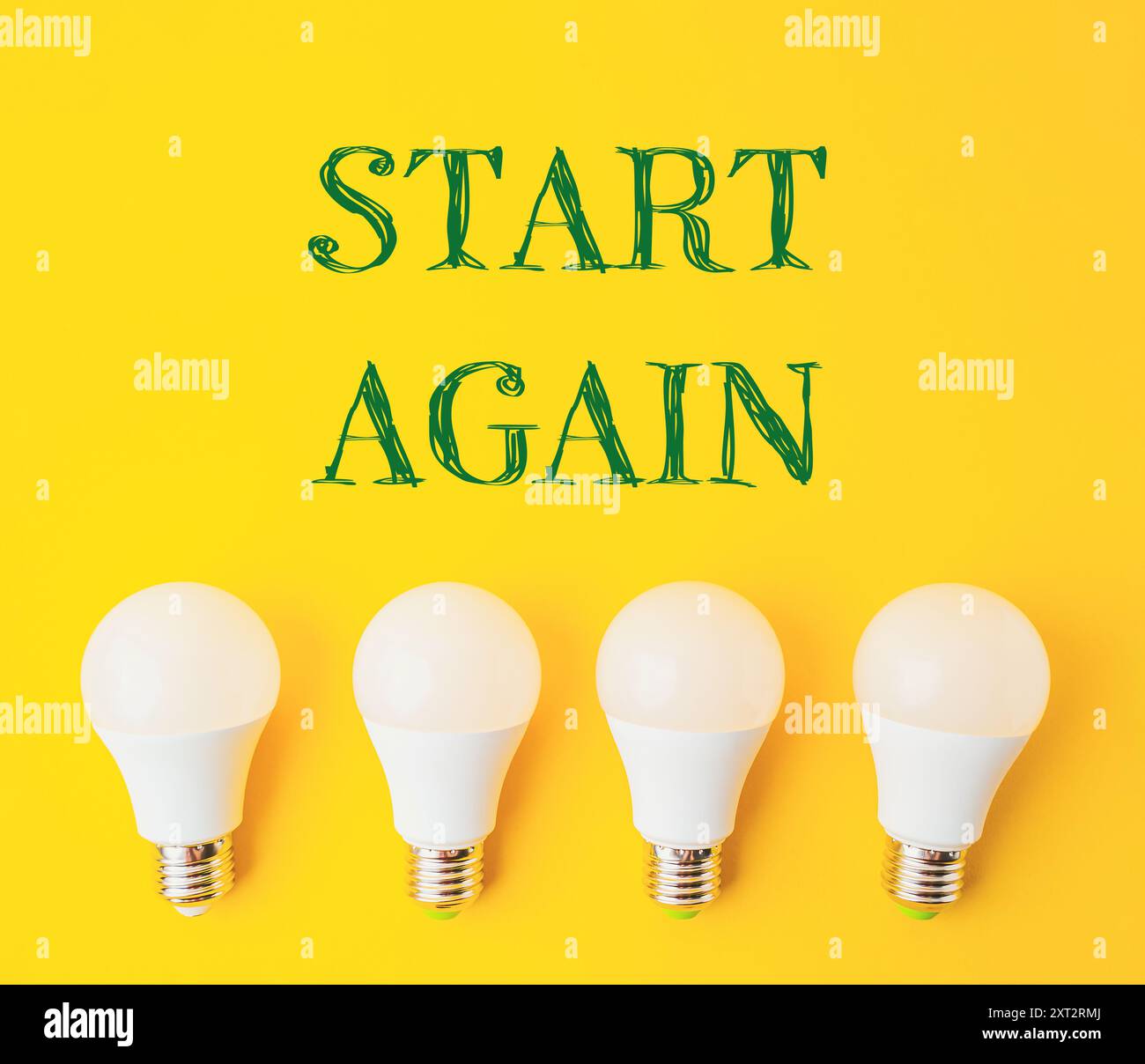 Vier weiße Glühlampen in einer Reihe auf gelbem Hintergrund. Das Wort „Start Again“ wird in grünen Buchstaben über den Lampen geschrieben, wodurch ein Gefühl von entsteht Stockfoto