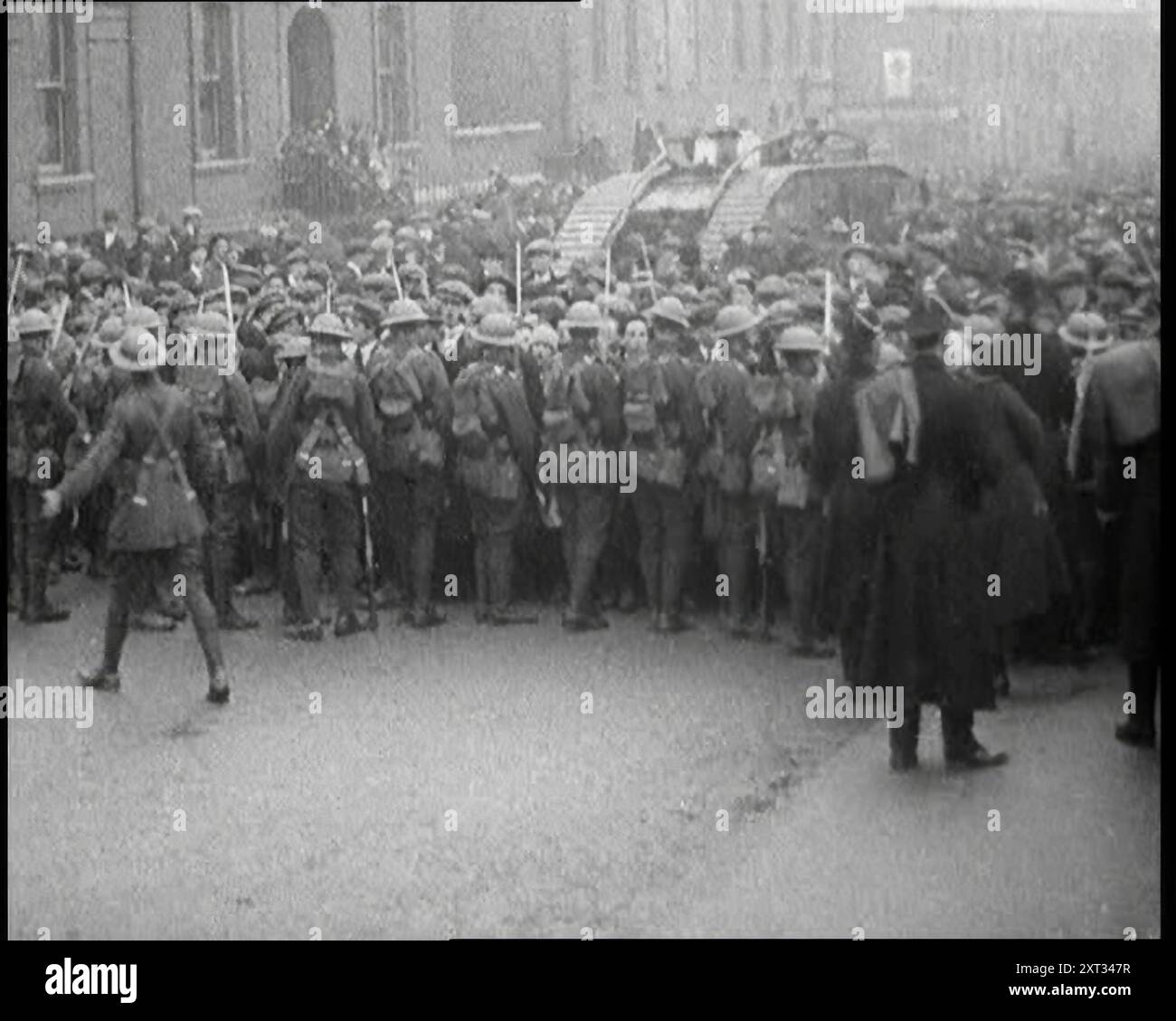 Britische Soldaten halten Massen von Demonstranten in Dublin zurück, während ein Panzer durchzieht, um sie zu zerschlagen, 1920. 'Vor Dublins Mountjoy Gefängnis, in dem so viele ihrer Freunde gefangen waren, zeigten wütende Menschenmassen den Geist ihrer Stadt durch Demonstrationen, dass nur schwere Rüstungen zerbrechen könnten. Aber könnte dieser Geist wirklich aufgelöst werden?" Aus "Time to Remember - the Plunge into Peace", 1920 (Reel 4); Ereignisse von 1920 - Hochzeiten, Frauenrechte, industrielle Unruhen und Probleme in Irland Stockfoto