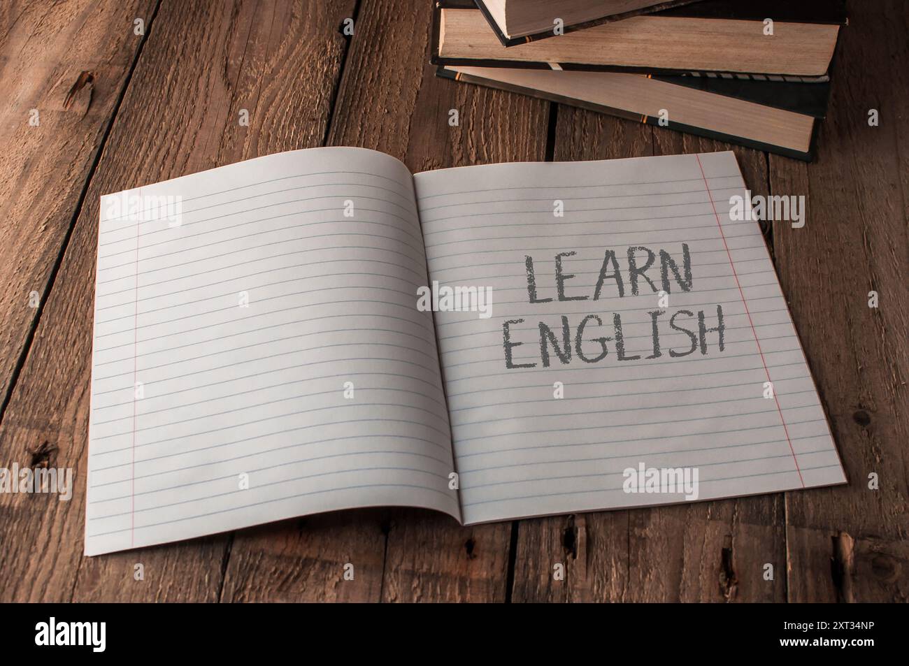 Ein Notizbuch ist offen für eine Seite, auf der das Wort Learn english steht. Das Notizbuch sitzt auf einem Holztisch Stockfoto