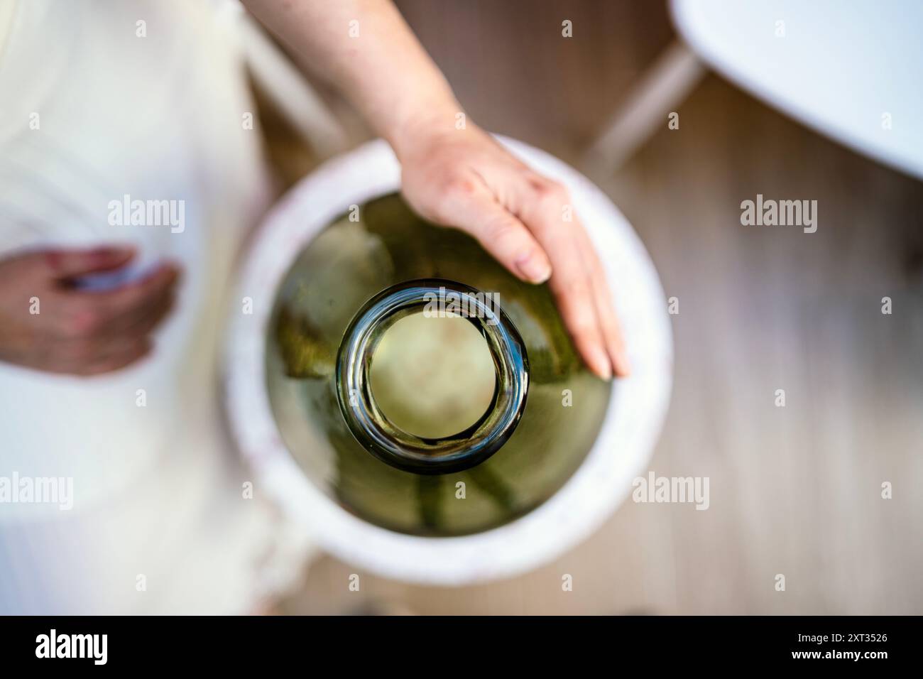 Weibliche Hände auf dunkelgrüner Glasblumenvase, Portugal Stockfoto