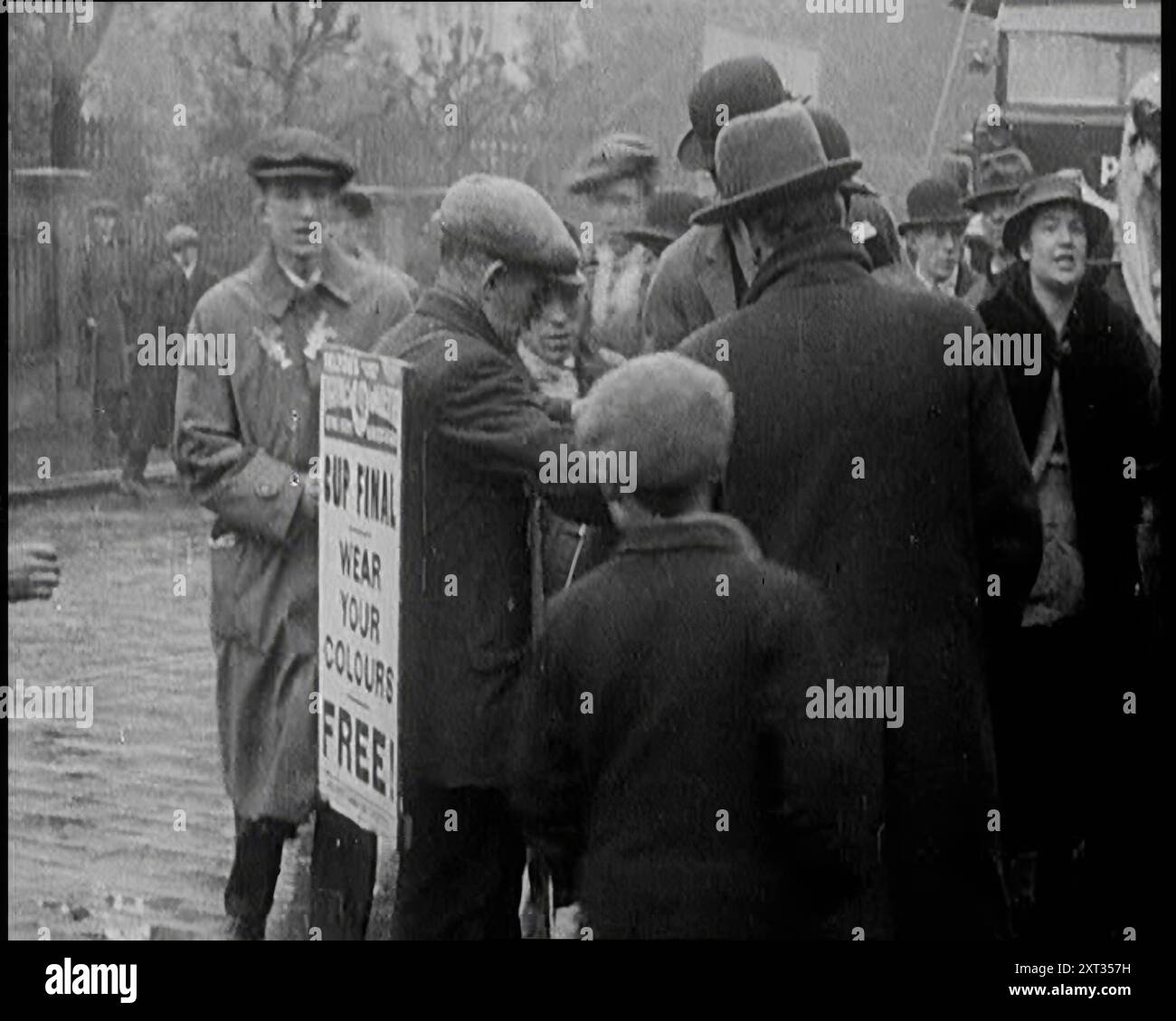 Ein Mann trägt ein Sandwich-Brett, der „Pathe Gazette“ mit der Aufschrift „Cup Final Wear Your Colours Free!“ (Pokal-Finale, Wear Your Colours Free!) anzeigt. Und Giving Away Badges, 1921. Aus "Time to Remember - The Time When Little Happened", 1921 (Reel 1); Ereignisse von 1921 - Irish treaty, Mad Stunts and Newspapers at Work. Stockfoto