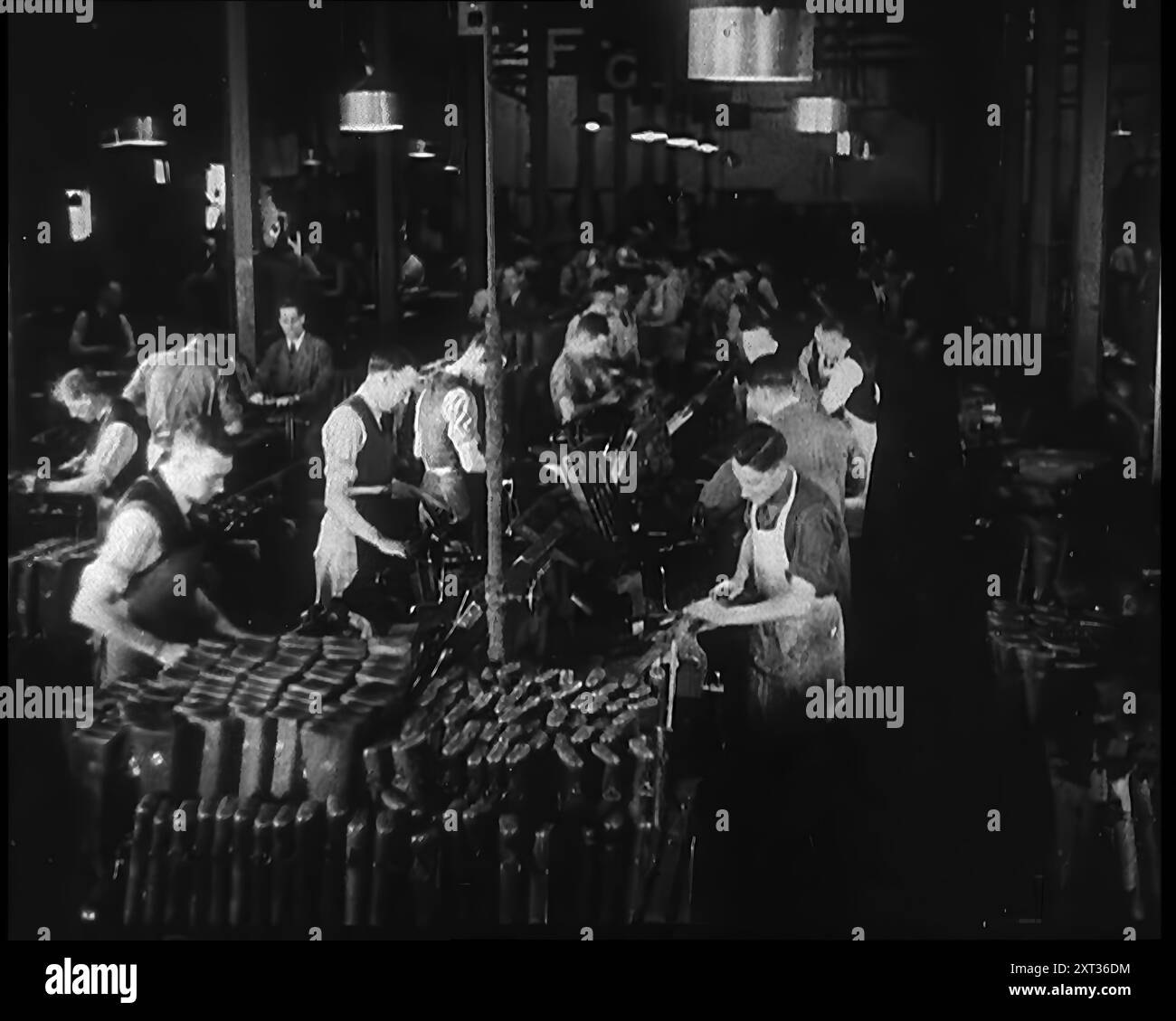 Männer, die in einer Fabrik arbeiten, 1940. Großbritannien während des Zweiten Weltkriegs. "...metallhungrige factories...noW Summen, um alle Waffen und Ausrüstungen zu ersetzen, die die britische Expeditionstruppe an den blutigen Stränden von Dünkirchen hinterlassen hat, und auch um neue Armeen auszustatten und zu bauen, sobald sie gebildet wurden." Aus „Time to Remember – Standing Alone“, 1940 („Reel 1“); Dokumentarfilm über Ereignisse der späten Monate 1940. Stockfoto