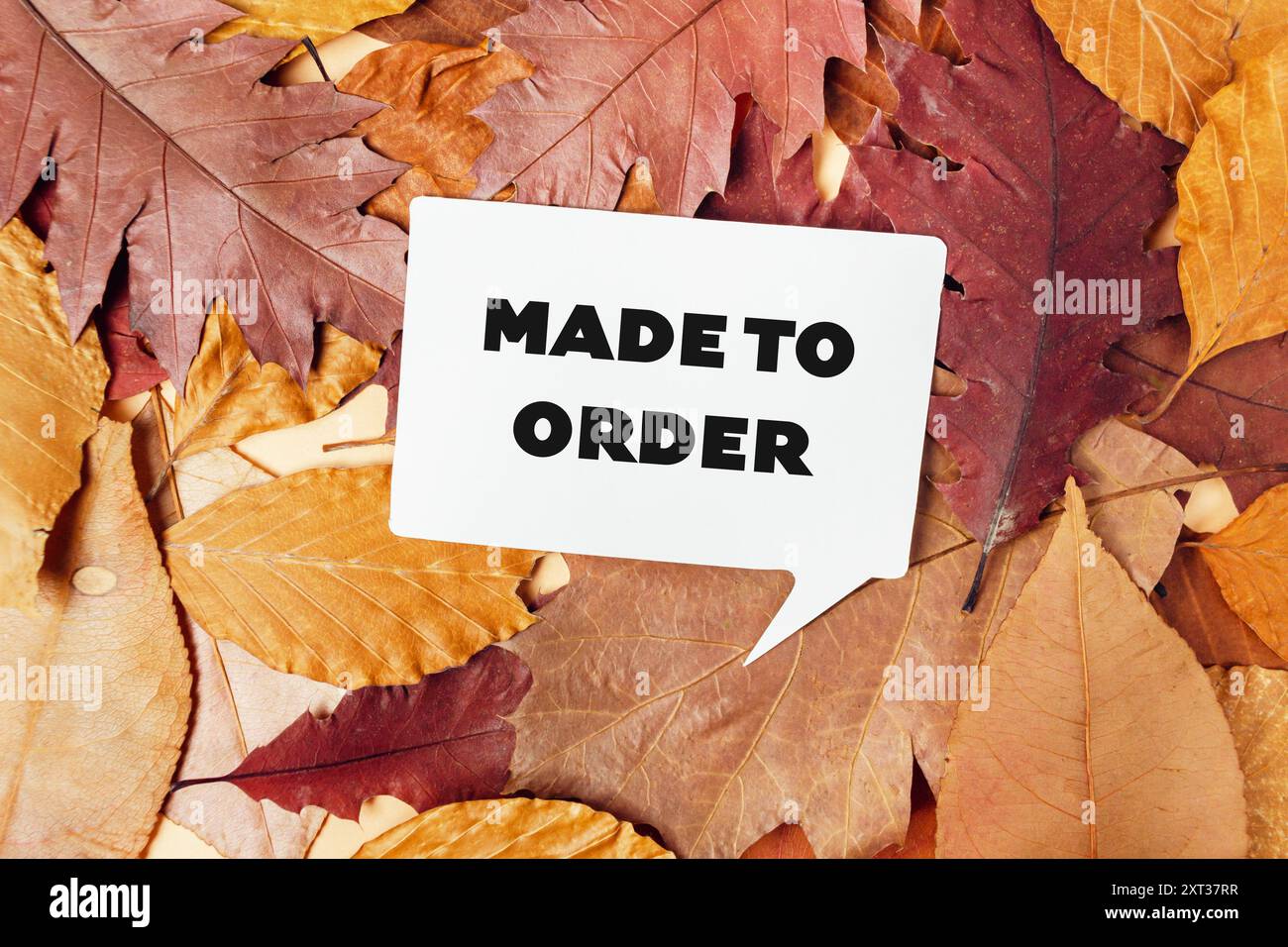 Ein weißes Schild mit der Aufschrift „Made to Order“ wird auf einem Herbststapel platziert Stockfoto