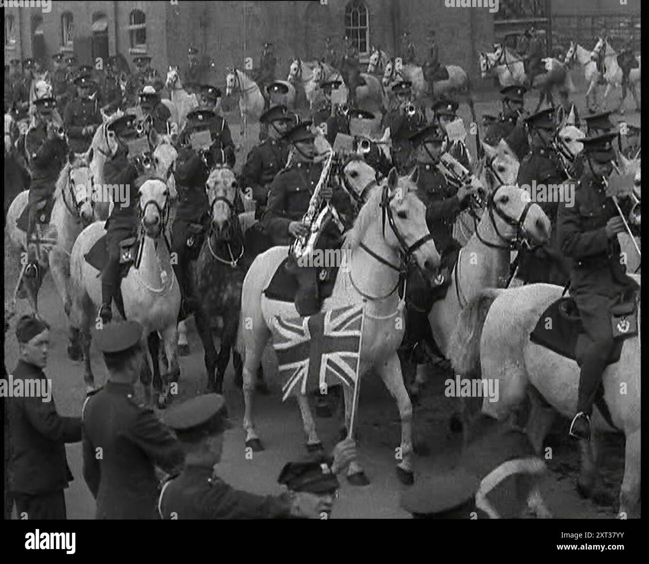 Britische Armee-Band auf dem Pferd, die eine Straße hinunterzieht, 1937. "...Trommeln, Knarren und Klappern in den Kasernen, die gefälschten Prozessionen, damit sich die Pferde an den Lärm und das Jubeln gewöhnen konnten, denn auch die Pferde müssen einen Sinn für Werte lernen, vor allem für eine Krönung." Aus "Time to Remember - Sense of Values", 1937 (Reel 1); Dokumentarfilm über die Ereignisse von 1937, Krieg im Fernen Osten, Aufbau bis Krieg in Europa. Stockfoto