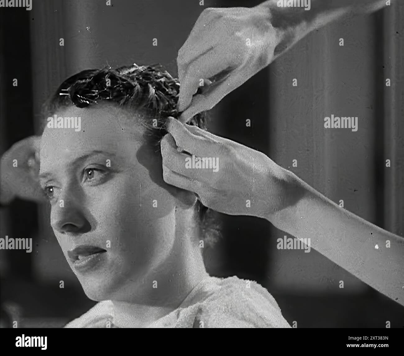 Eine Frau, deren Haare im "Victory"-Stil geschnitten wurden, 1942. Großbritannien während des Zweiten Weltkriegs. Die "Victory"-Frisur für Frauen. Nicht so sehr ein Stil, sondern ein Abschneiden, um zu verhindern, dass die Schlösser in der Arbeit verfangen werden. Denn die Frauen, die "die Maschinen arbeiteten, die die Dinge herstellten, die den Krieg gewinnen wollten", hatten nicht viel Zeit für Schnickschnack. Aus „Time to Remember – The End of the Beginning“, 1942 (Reel 3); Dokumentarfilm über Ereignisse von 1942 und Amerikas Eintritt in den Krieg. Stockfoto