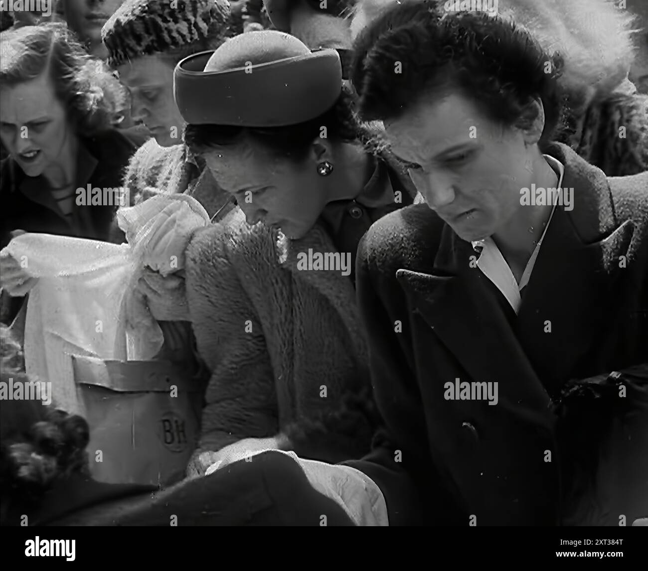 Frauen auf einem Markt, 1942. Großbritannien während des Zweiten Weltkriegs. "...die Flut hat sich gewendet, und zum ersten Mal seit der Drohung der Invasion läutet Großbritannien ihre Kirchenglocken, aber selbst als sie das Ende des Anfangs herausläuten, "jetzt, da Zweitbluse und Bluse die Coupons für kleine Alfie's Hosen retten würden". Aus „Time to Remember – The End of the Beginning“, 1942 (Reel 4); Dokumentarfilm über Ereignisse von 1942 und Amerikas Eintritt in den Krieg. Stockfoto