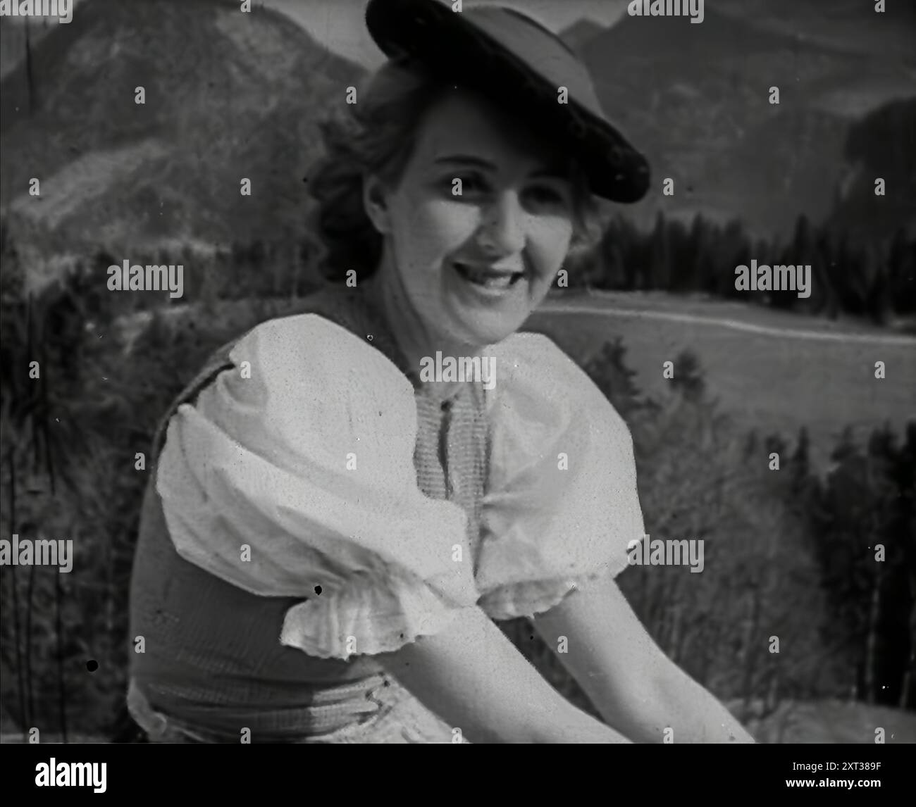Eva Braun sitzt auf einer Mauer, 1942. Zweiter Weltkrieg: Berchtesgaden in den deutschen Alpen. "...die Dame, die am NS-Hof als Eva Braun bekannt war, die 'Freundin' des Führers. Aus „Time to Remember – The End of the Beginning“, 1942 (Reel 4); Dokumentarfilm über Ereignisse von 1942 und Amerikas Eintritt in den Krieg. Stockfoto