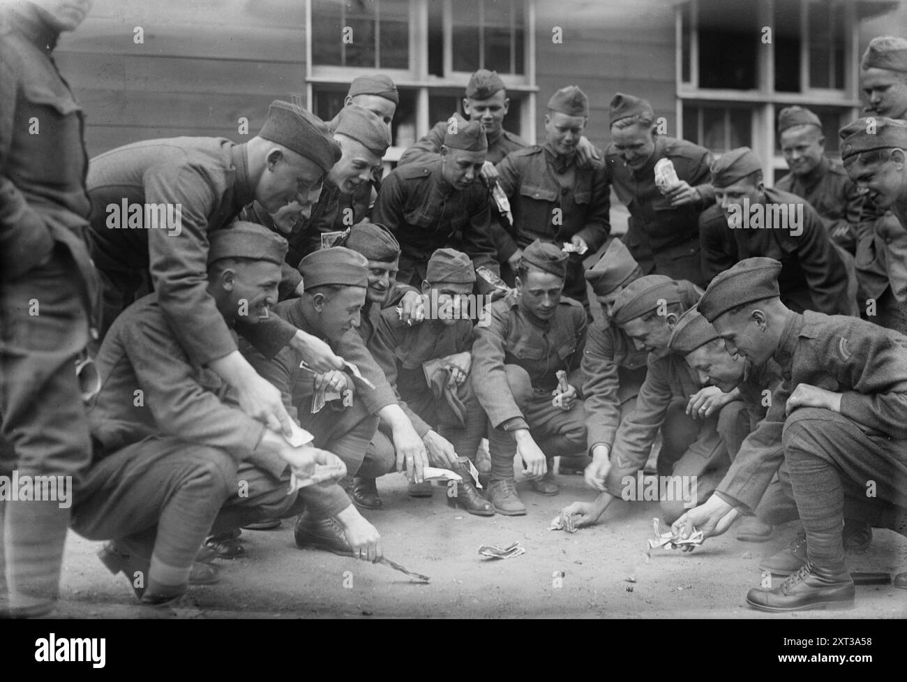 Glücksspiel zwischen 1915 und 1920. Zeigt eine Gruppe von Soldaten, die während eines Würfelspiels spielen. Schulterpflaster identifizieren sie als Mitglieder der 42. Infanteriedivision, der Rainbow Division. Stockfoto