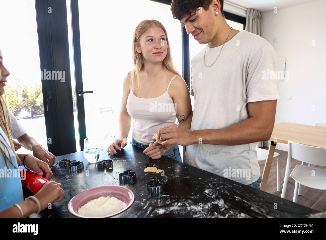 Familie Genießen Sie einen verbindenden Moment, während Sie in ihrer lichtdurchfluteten modernen Küche Kekse backen und Teamwork und familiäre Beziehungen präsentieren Stockfoto