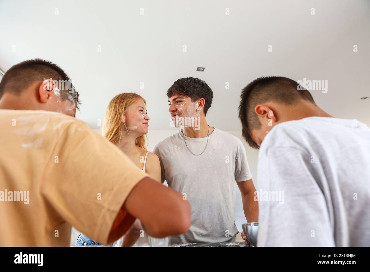 Die Geschwister nehmen an einer lustigen Kochstunde in ihrer Küche Teil, während sie Mehl über ihre Gesichter und Kleidung bekommen, während sie einen fröhlichen Moment zusammen genießen Stockfoto