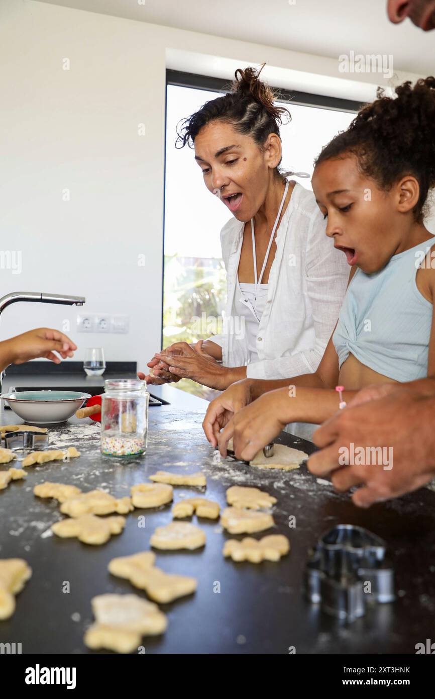 Ein fröhlicher Familienmoment, in dem Mutter und Kind gemeinsam Kekse in einer modernen Küchenumgebung zubereiten, die Freude und Teamgeist ausdrücken Stockfoto
