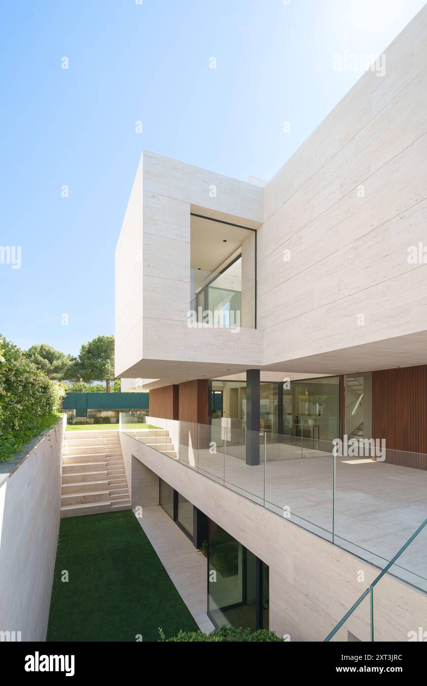 Dieses Bild zeigt ein luxuriöses, modernes Haus mit schlichter minimalistischer Architektur mit großen Glasfenstern, raffinierten Steinwänden und Holzakzenten Stockfoto