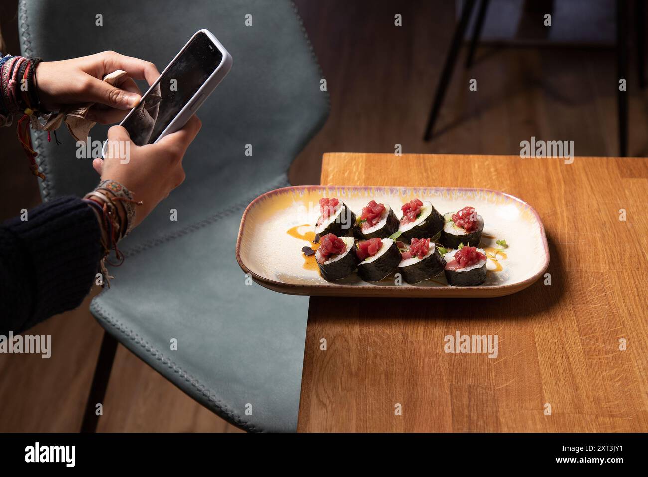 Eine Person nimmt ein Foto von frisch zubereiteten Sushi-Brötchen mit Thunfisch auf einem Designer-Teller auf und zeigt die Kunst der Lebensmittelfotografie Stockfoto