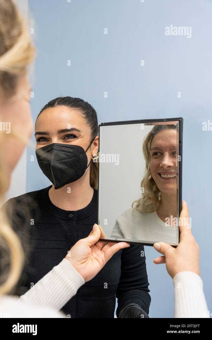 Eine Kosmetikerin führt einen Kunden durch das Mikroblading-Verfahren, skizziert Behandlungsbereiche und verwendet Gesichtsgeometrie für präzise Messungen. Stockfoto