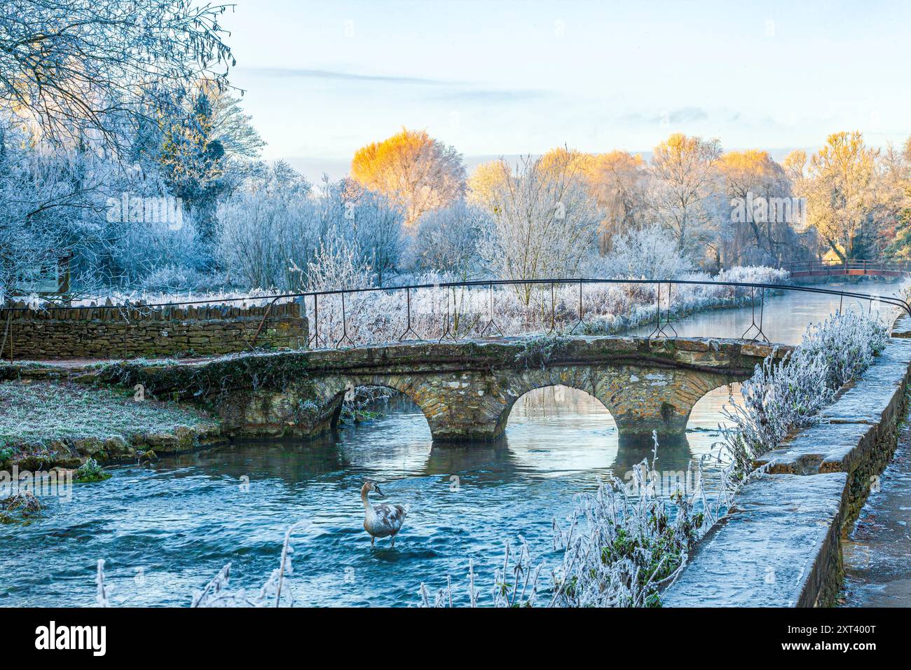 Die alte Steinbrücke über den Fluss Coln und Raureif auf Rack Isle bei Sonnenuntergang im Cotswold Dorf Bibury, Gloucestershire, England, Großbritannien Stockfoto