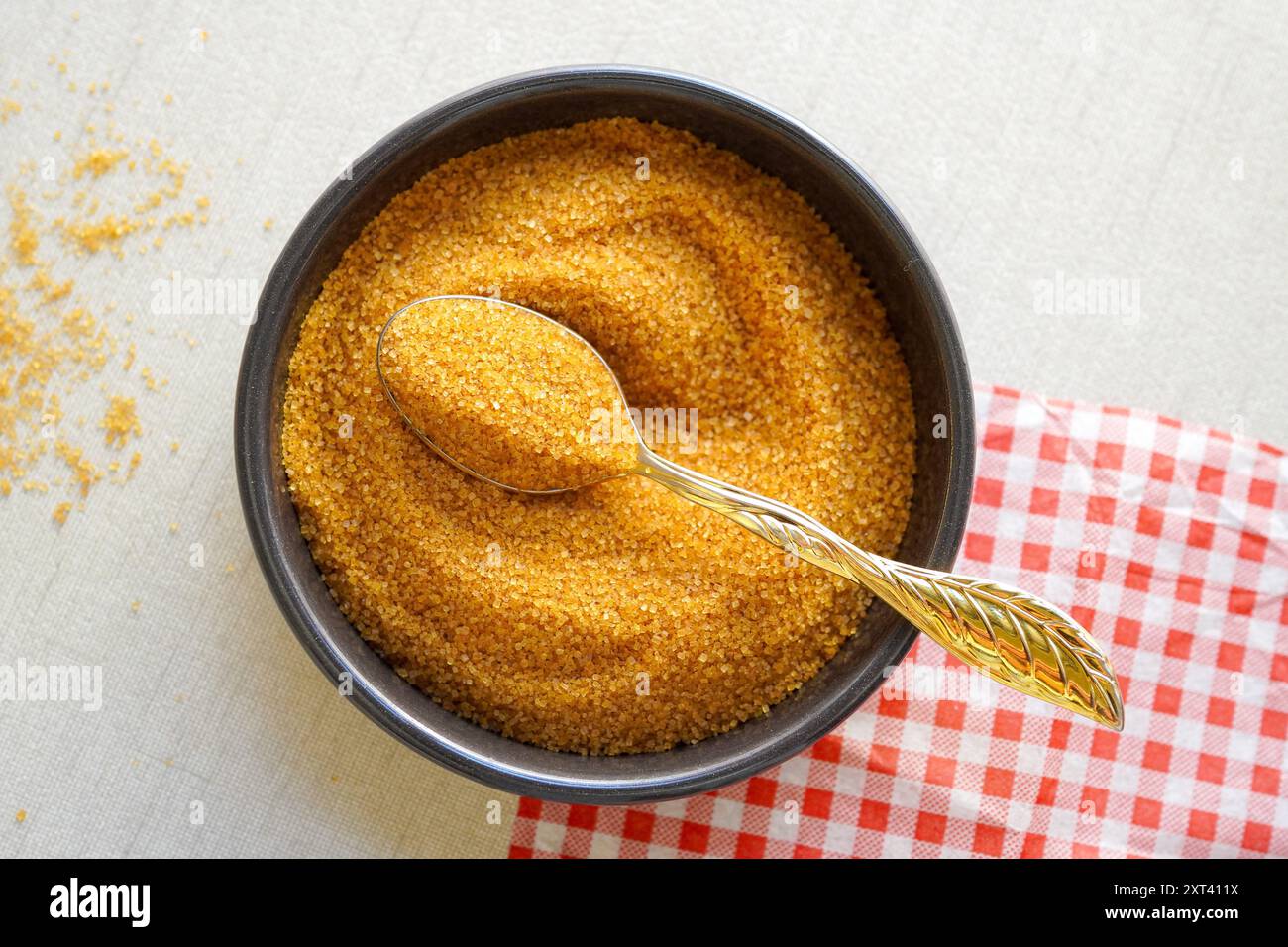 Nahaufnahme von braunem Zucker auf goldenem Löffel über weißem Hintergrund, Draufsicht Stockfoto