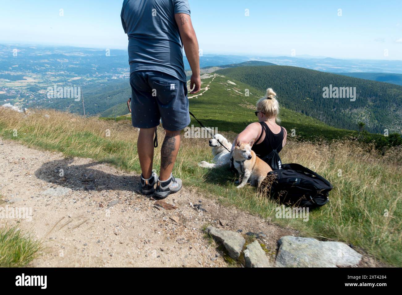 Mann und Frau mit ihren beiden Hunden ruht unter dem Gipfel von Sniezka Polen die Riesengebirge Karkonosze Szenenlandschaft Blick auf die polnische Seite Stockfoto