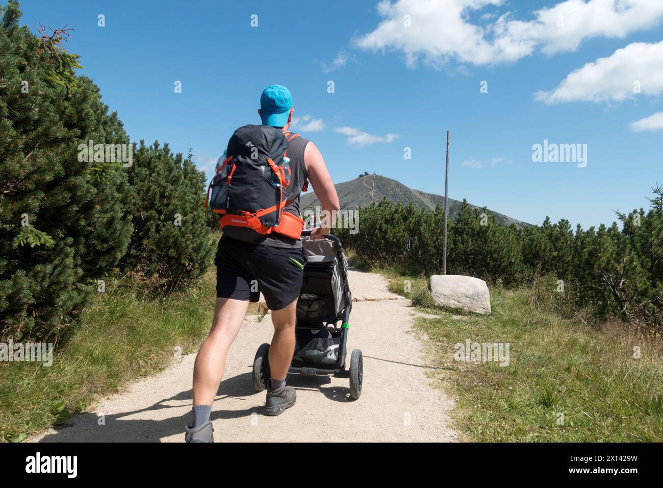 Mann schiebt einen Kinderwagen auf einem Bergweg den Riesengebirge Krkonose Nationalpark Tschechische Republik Snezka Hintergrund Stockfoto