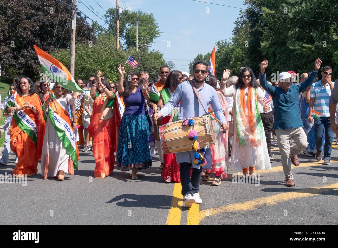 Unter der Leitung eines Schlagzeugers feiert eine fröhliche Gruppe von Märschen den Jahrestag der Unabhängigkeit Indiens bei der New City India Day Parade. Stockfoto