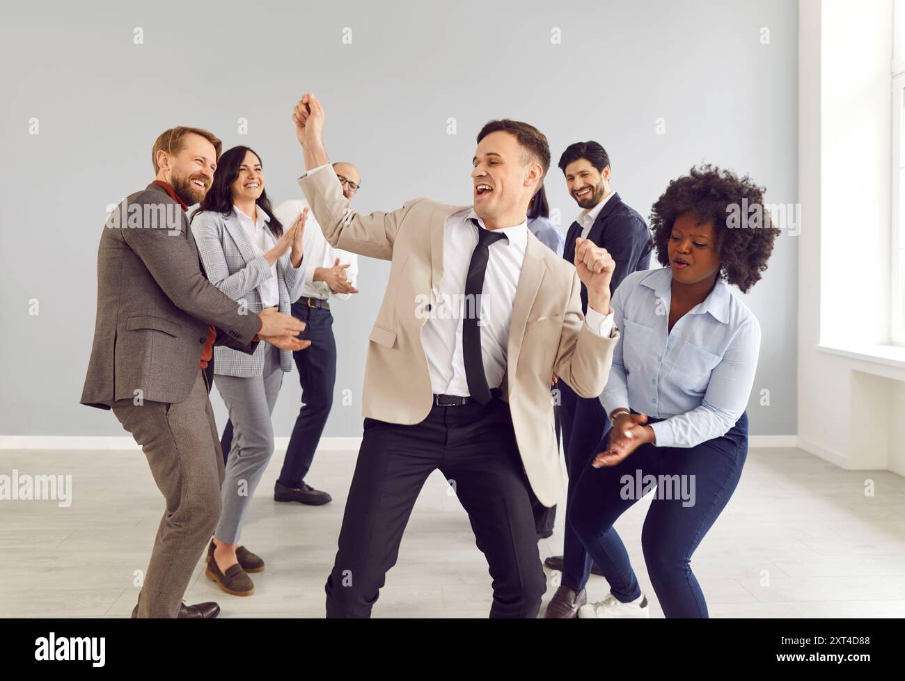 Glückliche Kollegen im Büro haben Spaß, verschiedene gemischte Freunde tanzen zusammen und feiern Stockfoto