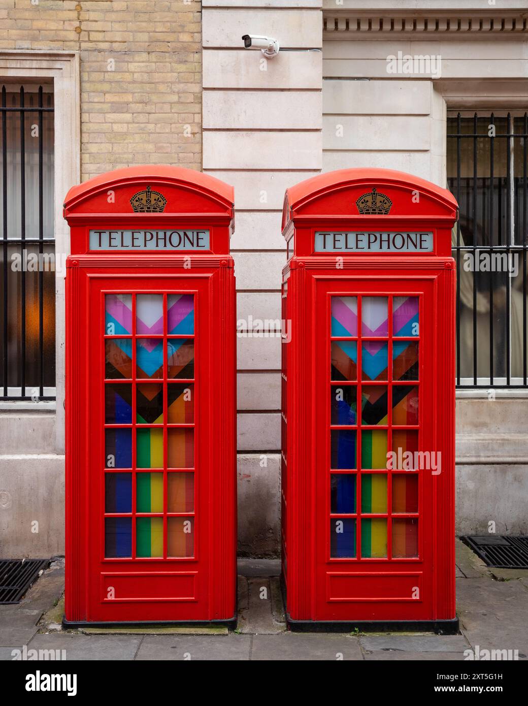 Zwei rote Telefonzellen mit Regenbogenflaggen im Broad Court, London, um die Ecke des ehemaligen Magistrates' Court und der Polizeistation Stockfoto