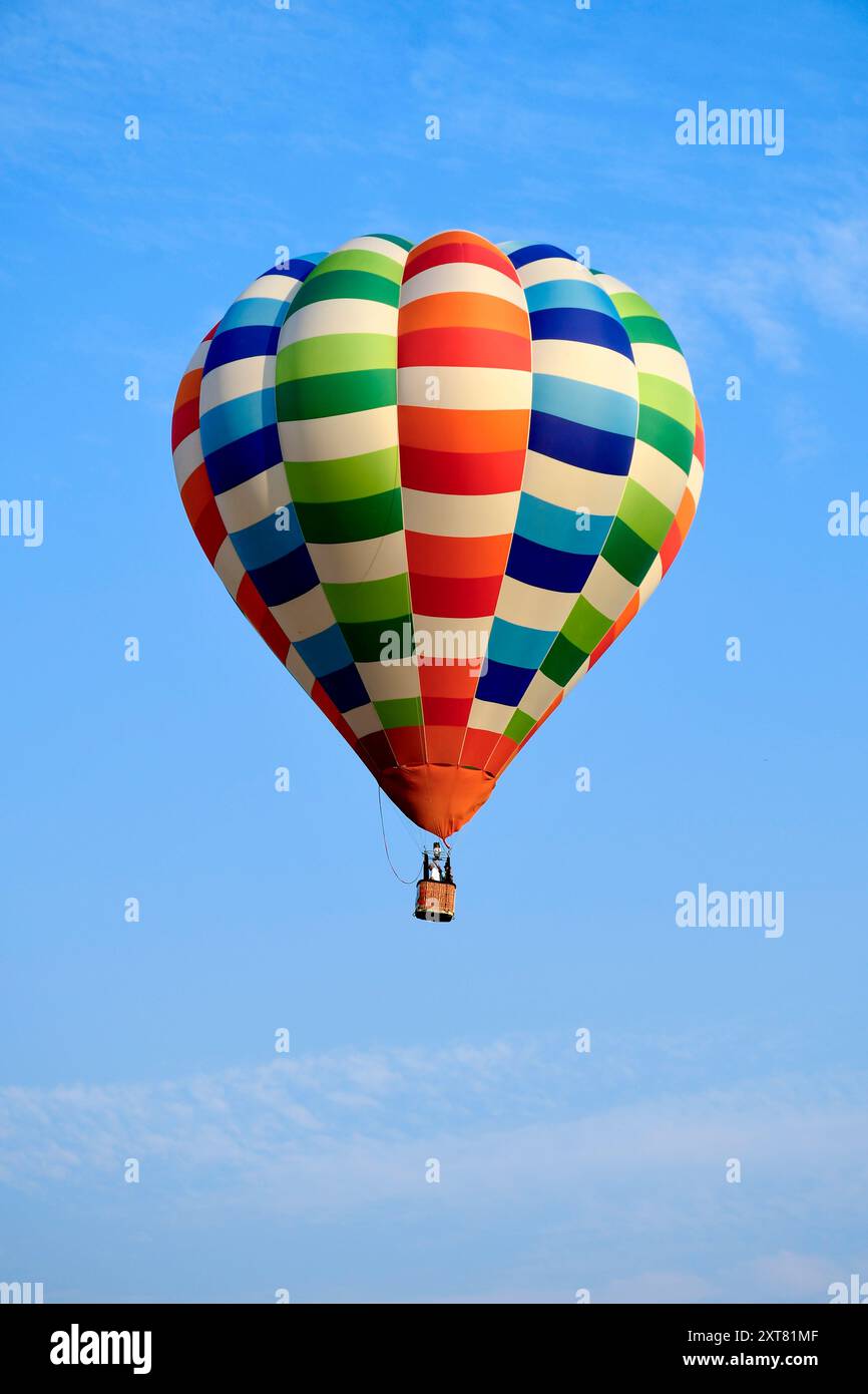 Farbenfroher Heißluftballon über blauem Himmel im hellen Sonnenlicht. Stockfoto