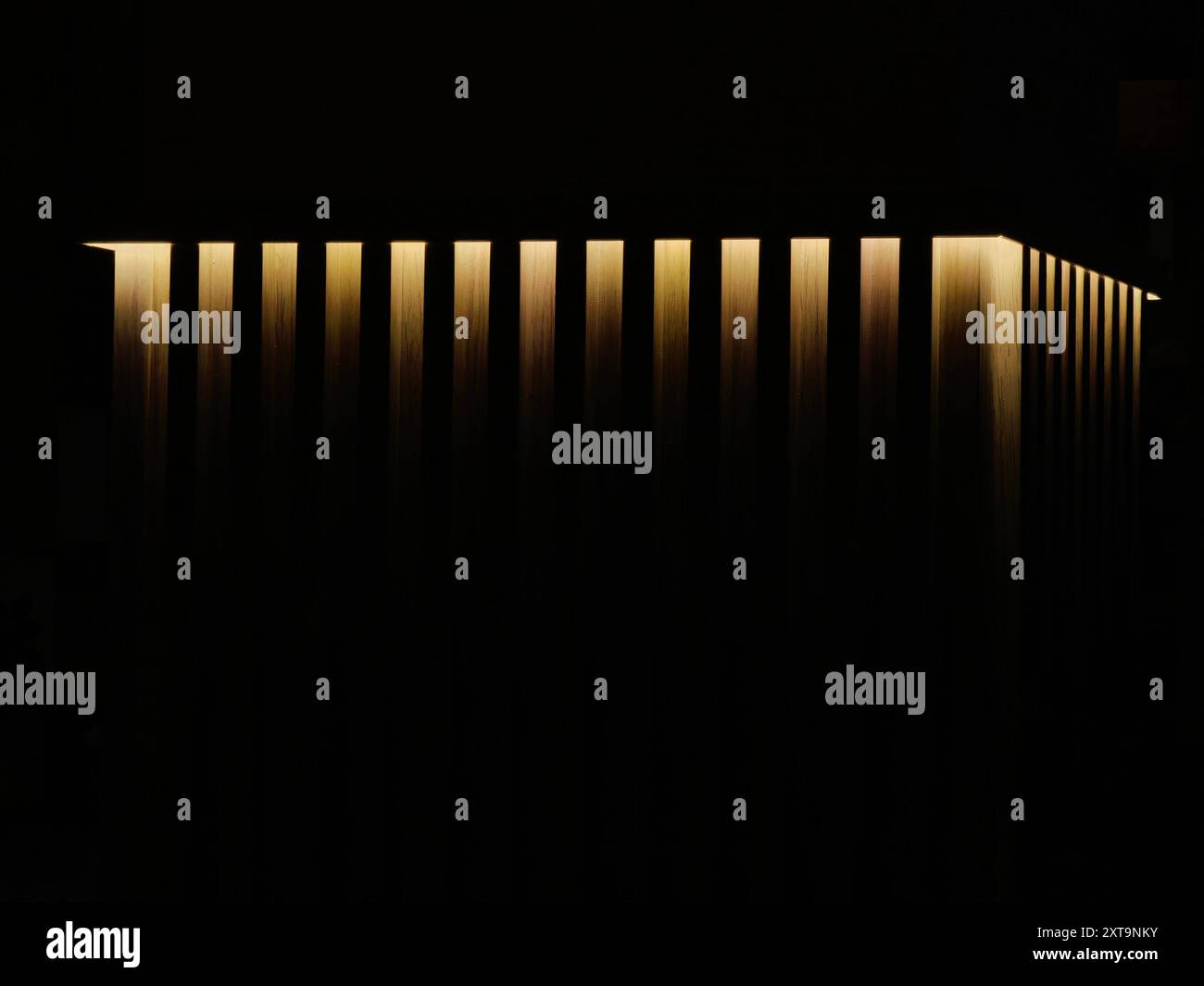 Beleuchtete Säulen mit dekorativem Licht: Muster und Textur auf dem Wandhintergrund. Goldenes Glühen. Stockfoto