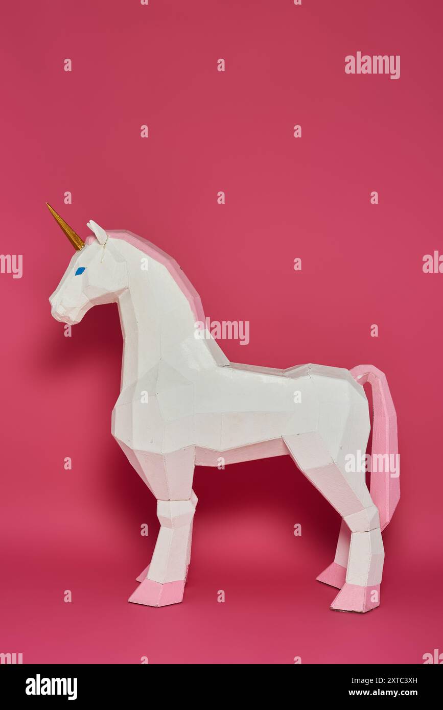 Ein weißes Einhorn mit pinkfarbenen Akzenten steht vor einem rosafarbenen Hintergrund. Stockfoto