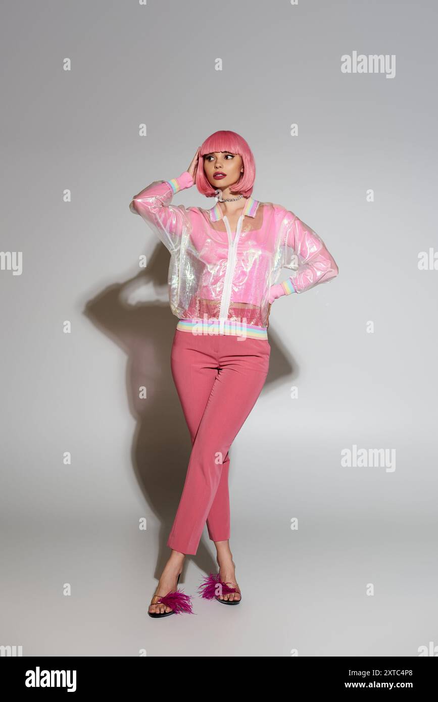 Eine Frau posiert in einer rosa transparenten Jacke, einer rosa Hose und gefiederten Schuhen. Stockfoto