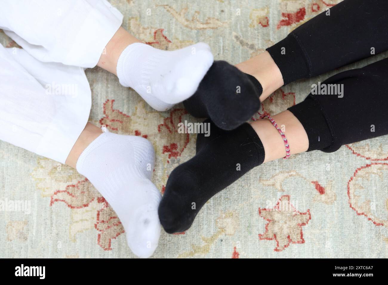 Zwei Mädchen spielen mit Füßen schwarz-weiße Socken, die Fußsohlen aneinander drücken Knöchelarmband Fußkettchen spielen Fussball Stockfoto