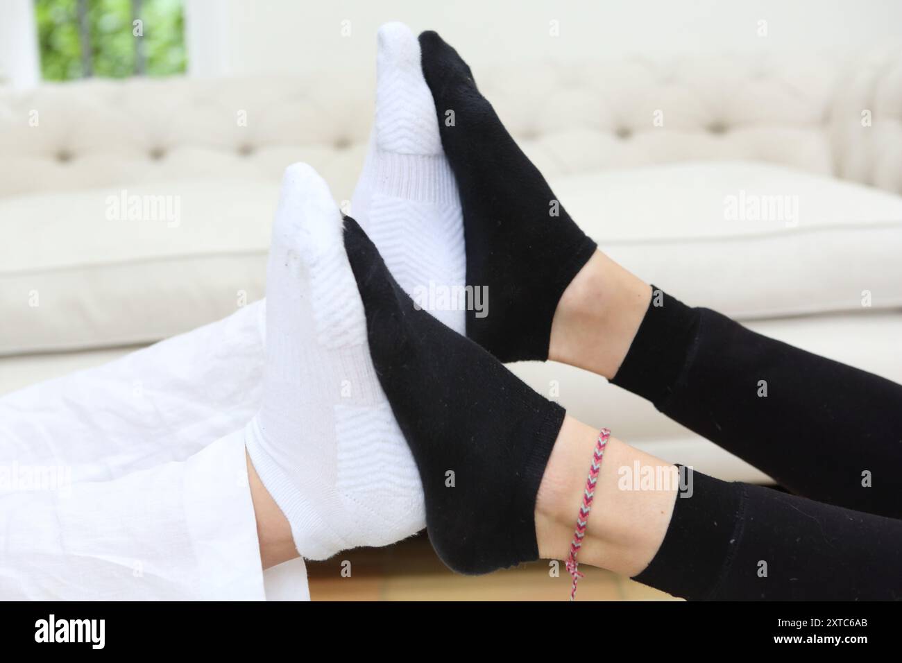 Zwei Mädchen spielen mit Füßen schwarz-weiße Socken, die Fußsohlen aneinander drücken Knöchelarmband Fußkettchen spielen Fussball Stockfoto